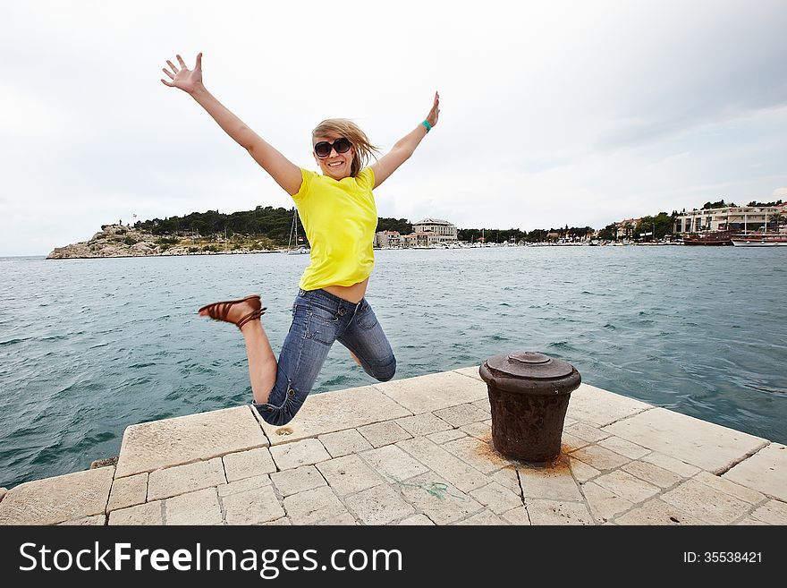 Young cheerful woman jumping on the pier