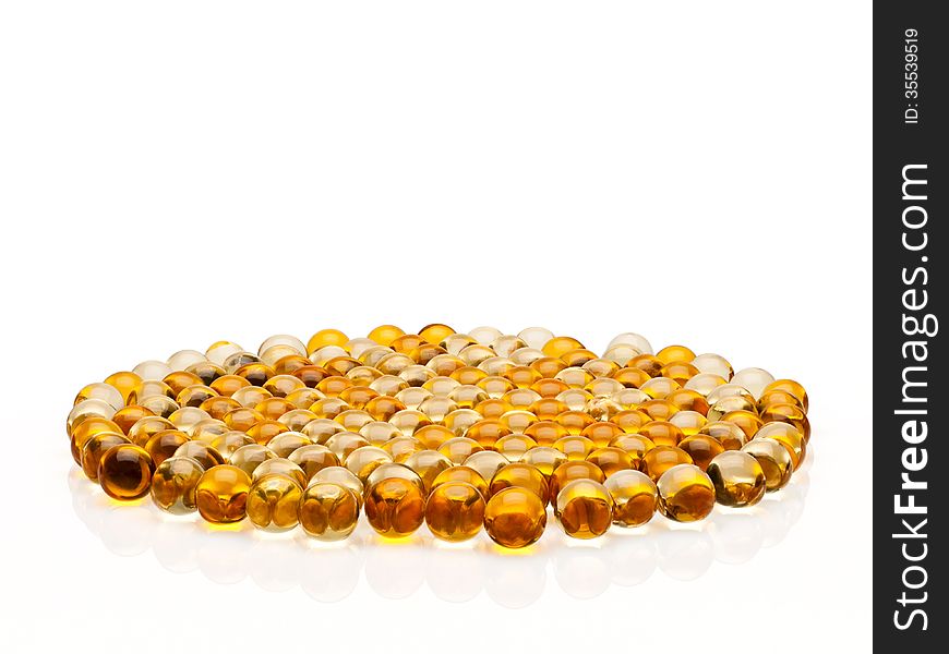 Many transparent, yellow pills with cod-liver oil on a black white background
