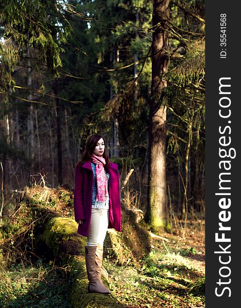 Woman in pink coat in sunshine forest