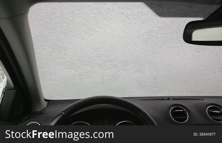 A man cleans his car from snow and ice. A man cleans his car from snow and ice