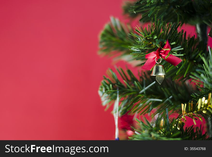 Small Bell On Christmas Tree On Red Background