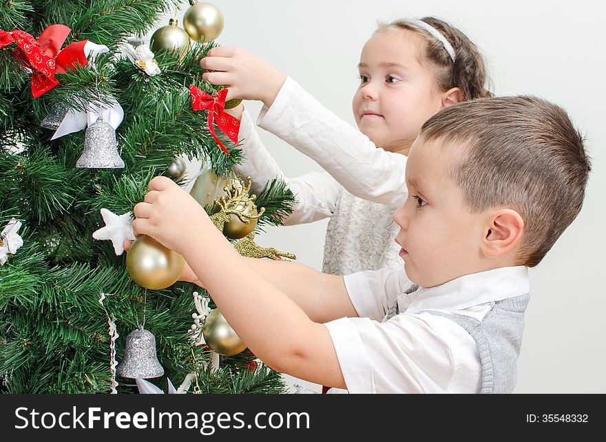 Children decorating Christmas tree with balls. Children decorating Christmas tree with balls.