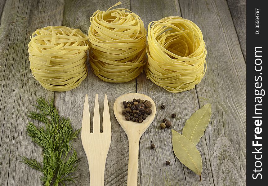 Rolled noodles with wooden spoon and fork on the wooden table. Rolled noodles with wooden spoon and fork on the wooden table