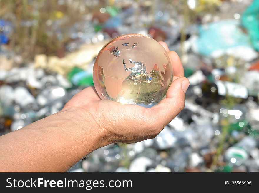 Globe in hands on garbage background.