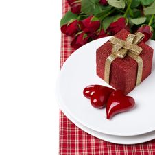 Red Gift Box And Two Hearts On A Plate, Roses In The Background Royalty Free Stock Photo