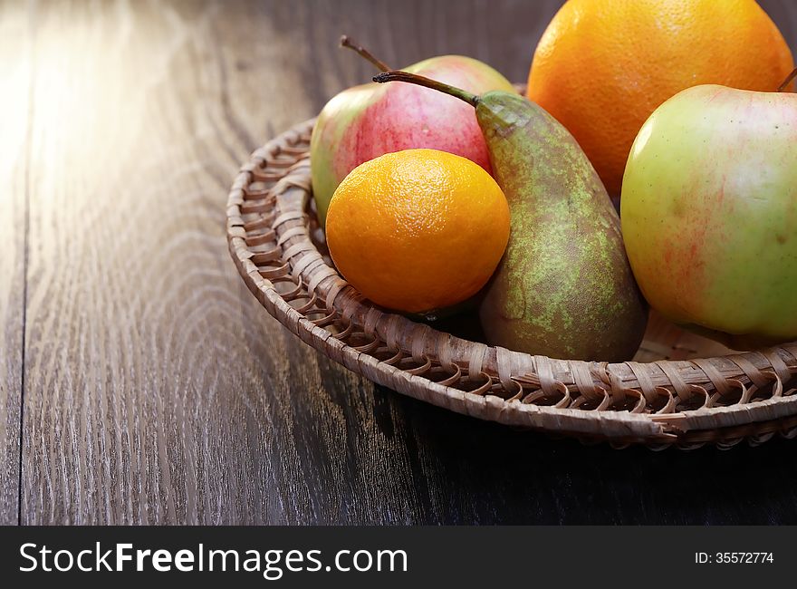 Set of various fruits in wicker basket on wooden table. Set of various fruits in wicker basket on wooden table