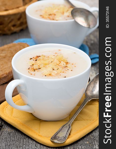 Cream soup of cauliflower with cheese in a cups, vertical, close-up