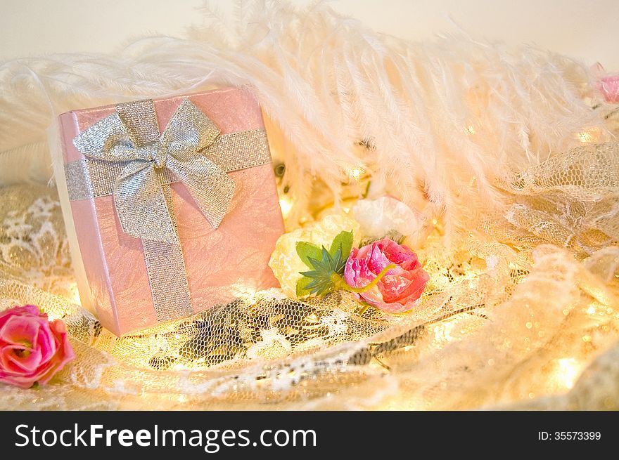 Pink gift box with roses and white feather background. Pink gift box with roses and white feather background
