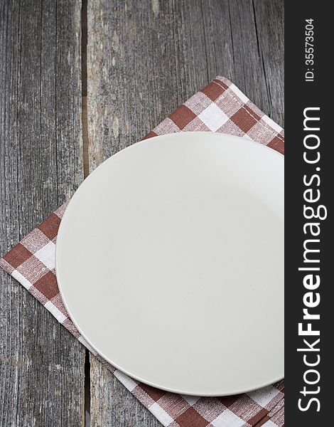 Empty plate on a napkin on wooden table, concept