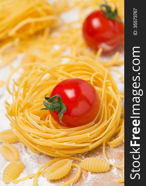 Italian egg pasta nest, cherry tomatoes on a cutting board, selective focus, vertical