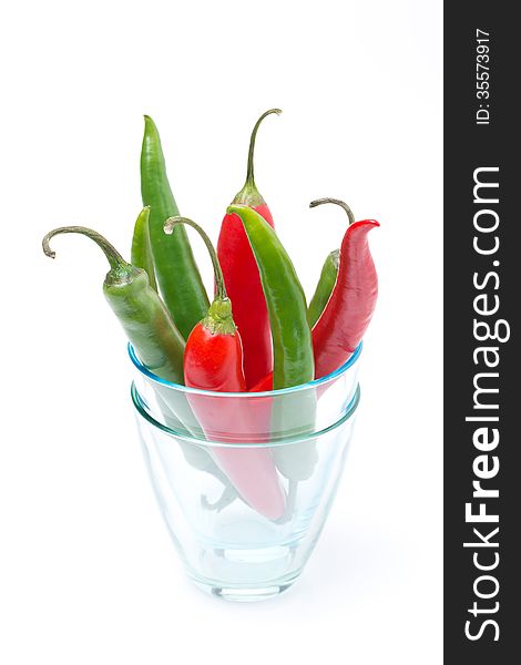 Red and green chili peppers in a glass, isolated on white