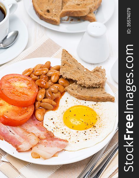 Traditional English breakfast with fried eggs, bacon and beans, vertical, top view