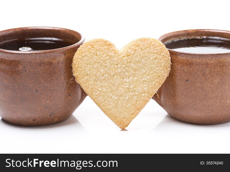 Two cups of coffee and cookies in the shape of hearts