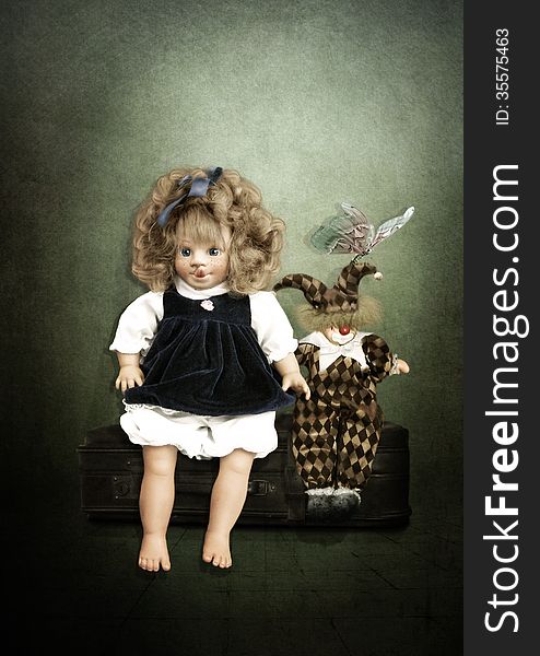 Doll and Clown are sitting on a suitcase on a vintage background. Doll and Clown are sitting on a suitcase on a vintage background