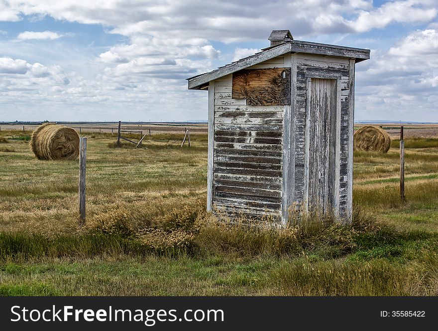 Abandoned outhouse under a prairie sky