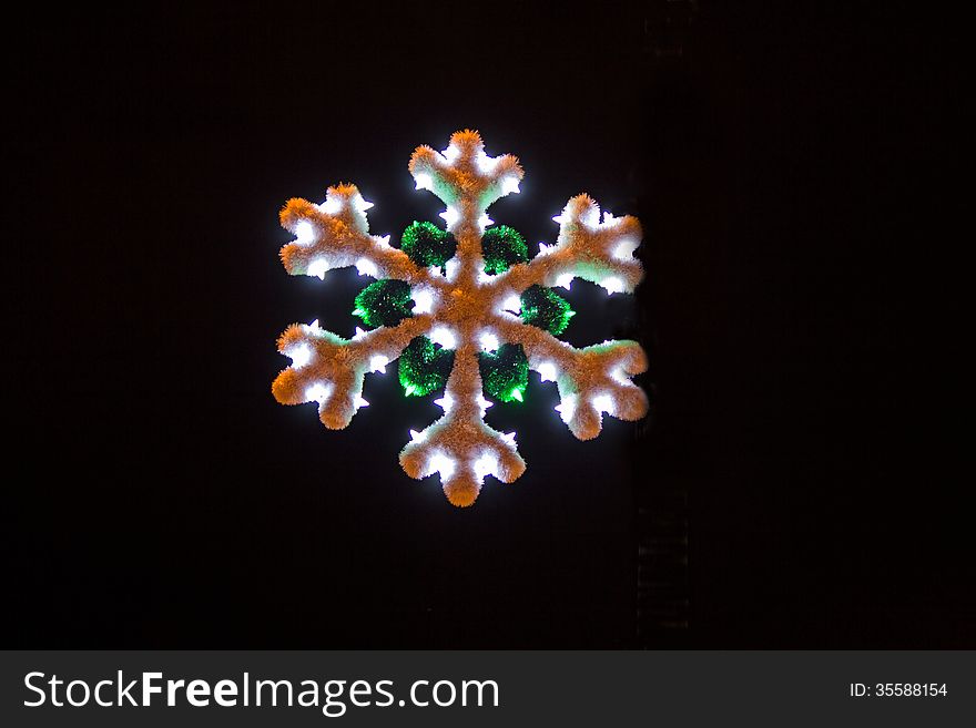 Lit white and green Christmas snowflake on a black background. Lit white and green Christmas snowflake on a black background