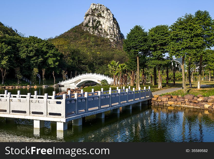 Chinese garden landscape:winding corridor,stone arch bridge and hill.