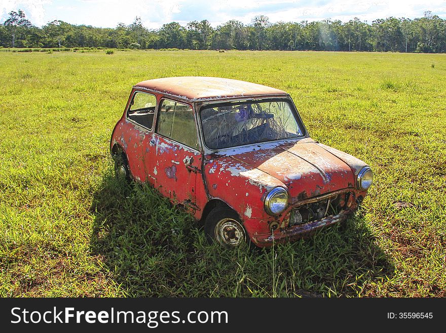 Red Mini-Minor car abandoned in cow pasture. Red Mini-Minor car abandoned in cow pasture