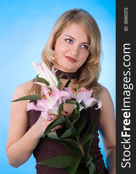 The attractive woman with a bouquet of lilies isolated on a dark blue background.