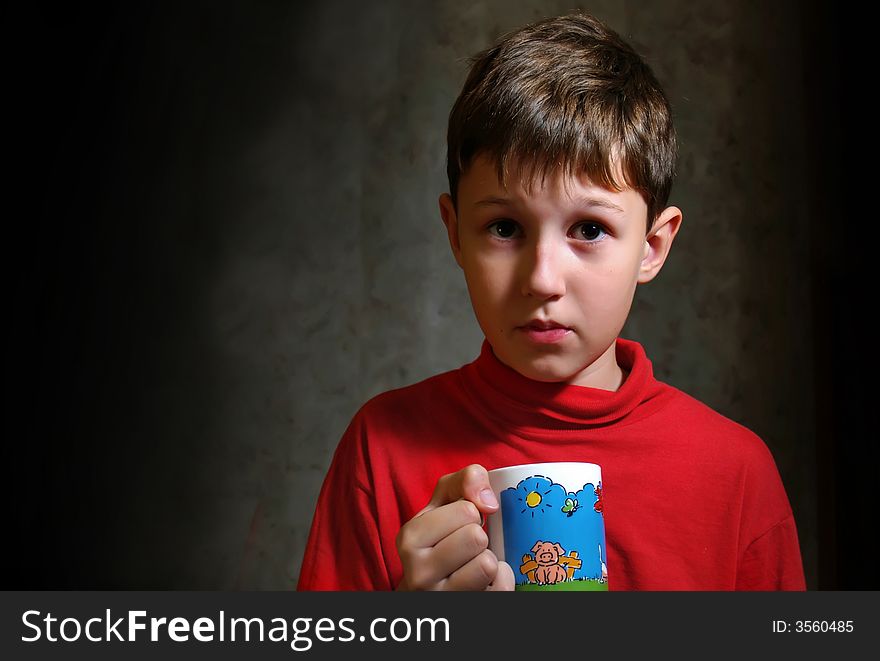 The little boy drinking a tea from color cup. The little boy drinking a tea from color cup