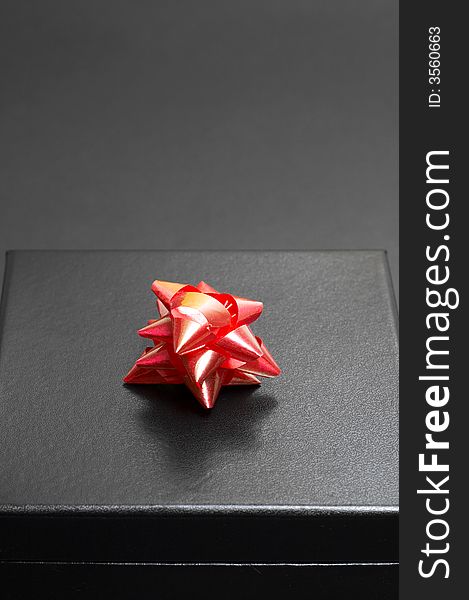 Black gift box with a red bow on black background. Black gift box with a red bow on black background