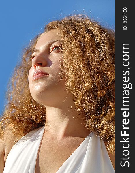 Face of female with curling hair on the blue sky. Face of female with curling hair on the blue sky