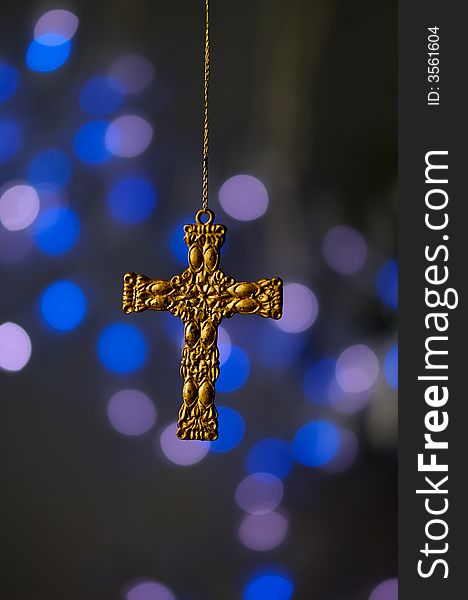 An image of a gold cross ornament on a blue background