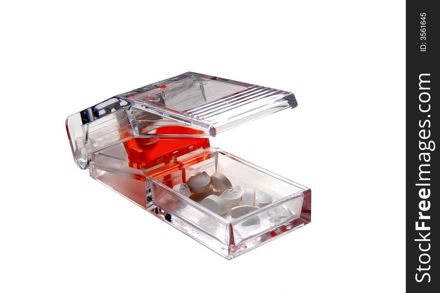 A clear pill cutter / splitter with pills and tablets.