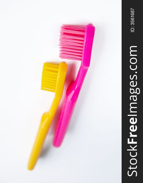 Two colored pink and yellow tooth brushes isolated on white