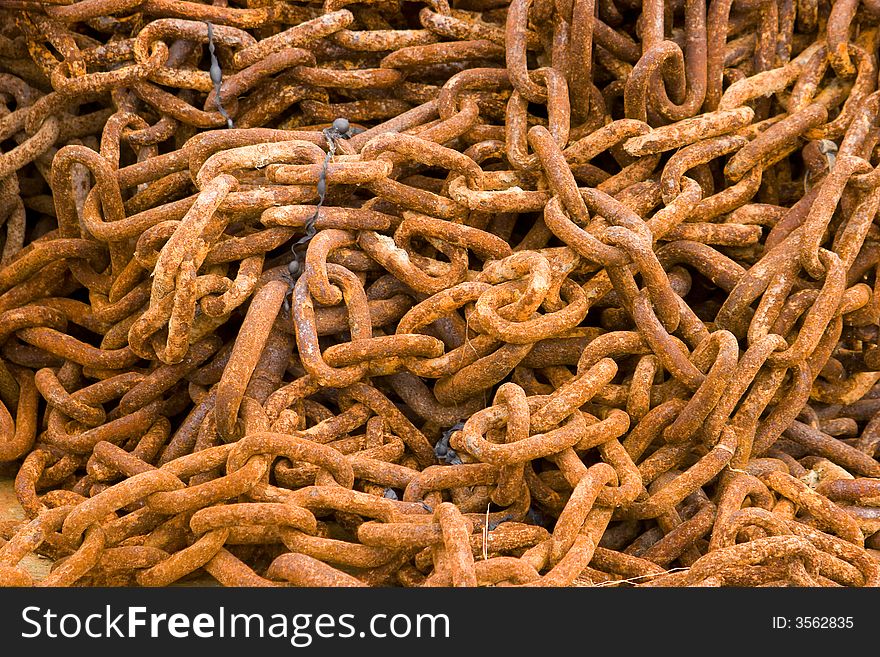 A pile of rusty chains encrusted with salt lying on the beach