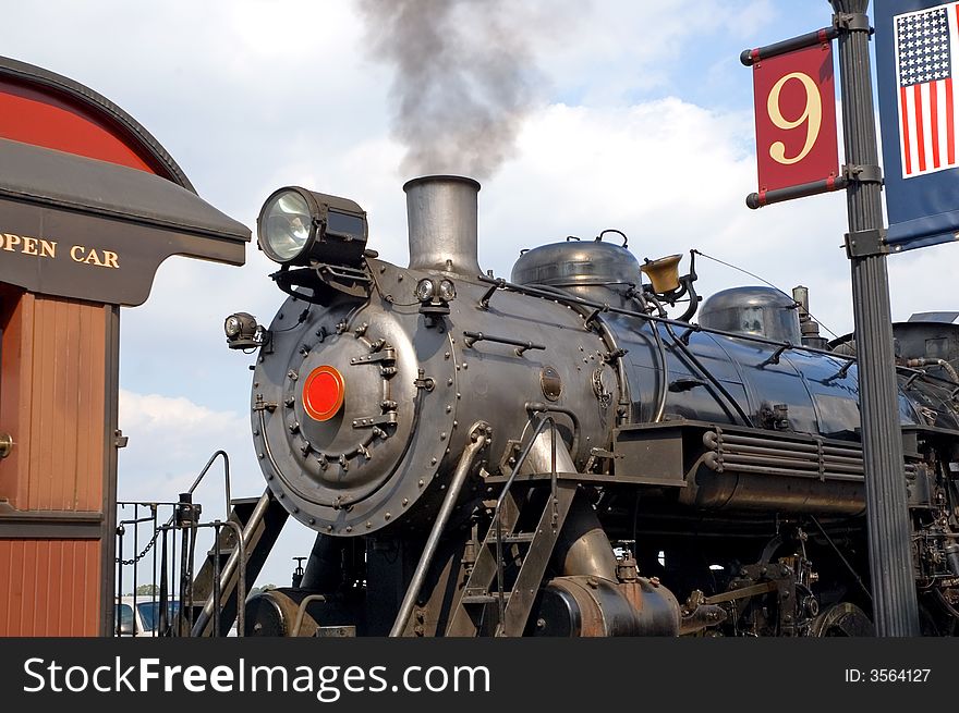 A partial view of a large, authentic steam locomotive and engine, including the coal burning boiler as it waits at a train stations for passengers to board. A partial view of a large, authentic steam locomotive and engine, including the coal burning boiler as it waits at a train stations for passengers to board.