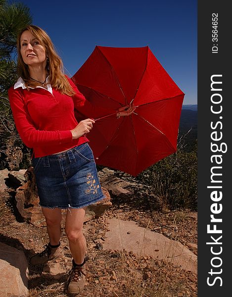 A woman takes a hike with a red umbrella. A woman takes a hike with a red umbrella.