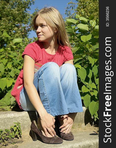 Blond smiling girl sitting on footsteps