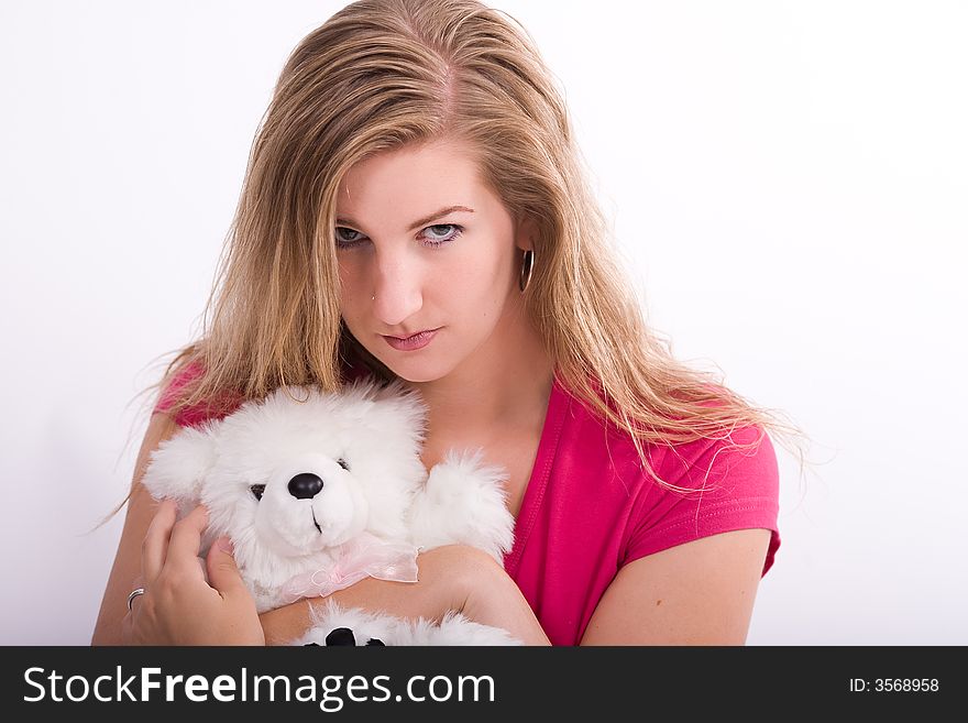 Young woman hugs her teddy bear while looking offended or angry. Young woman hugs her teddy bear while looking offended or angry.