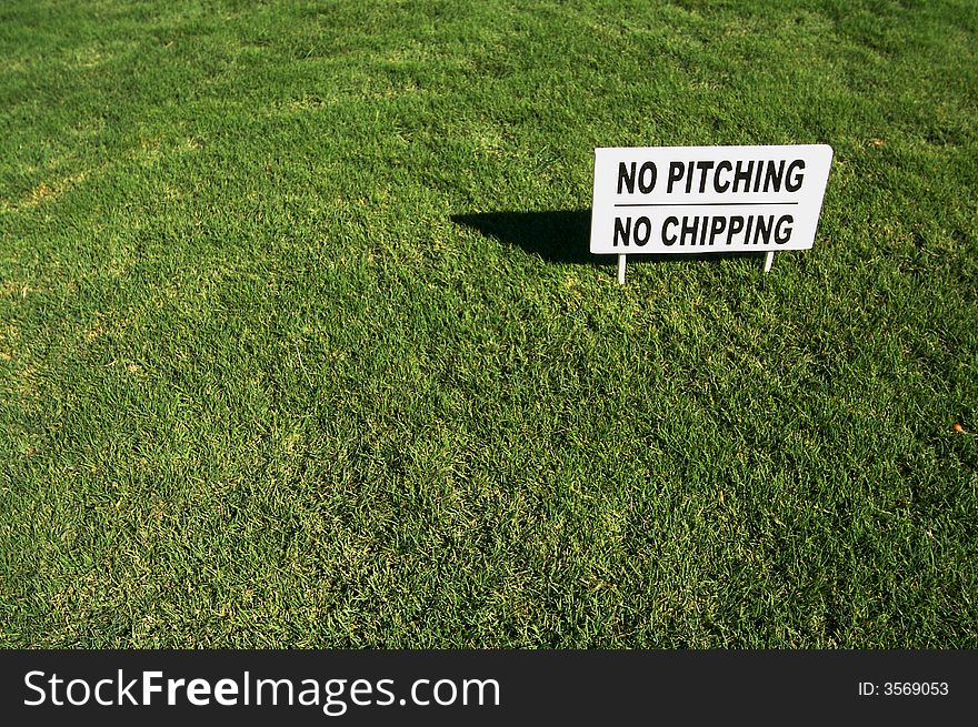 No Pitching, No Chipping sign in Lush Green Golf Course Grass.