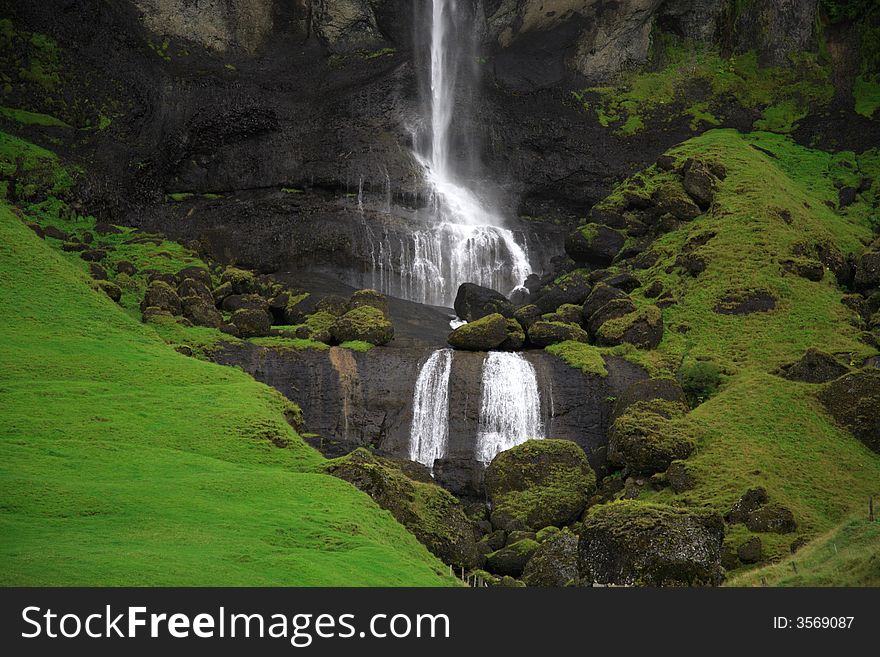 Waterfall and green hills in Iceland