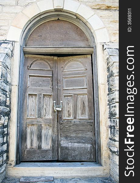 An old weathered door of a church building chained and padlocked shut. An old weathered door of a church building chained and padlocked shut.