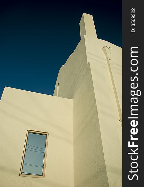 The sharp angles and lines of an adobe white building contrasted against the deep sky above. The sharp angles and lines of an adobe white building contrasted against the deep sky above.
