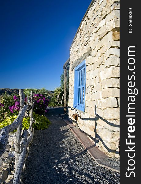 The side of a stone building with a brigh blue window taken against an amazing bright blue sky. The side of a stone building with a brigh blue window taken against an amazing bright blue sky.