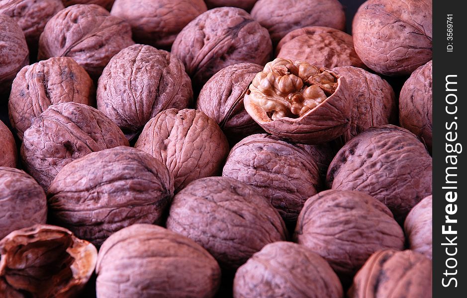 Background with walnuts and one crushed walnut