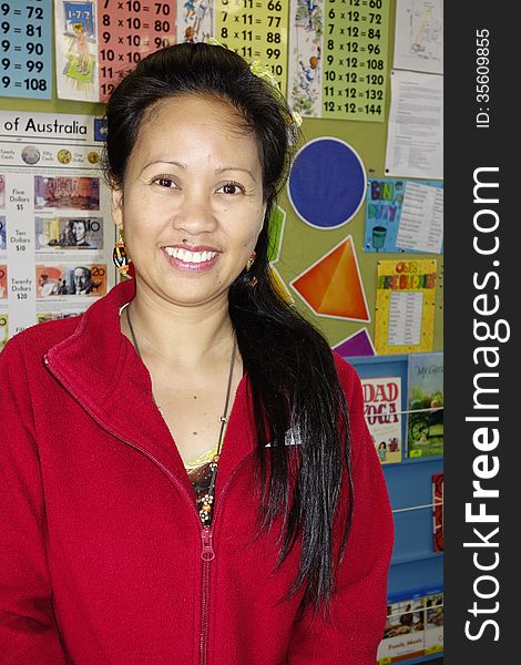 A proud primary school teacher from the Phillipines smiles happily in her classroom. A proud primary school teacher from the Phillipines smiles happily in her classroom.