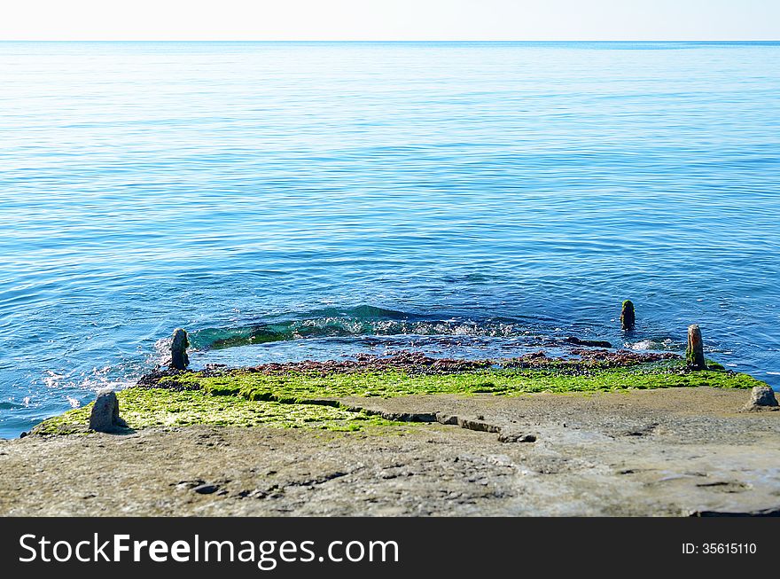 Stone jetty with green algae, stretching into the sea. Stone jetty with green algae, stretching into the sea