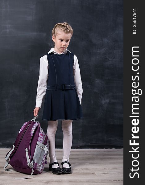 Latecomers little schoolgirl with backpack near blackboard. Latecomers little schoolgirl with backpack near blackboard