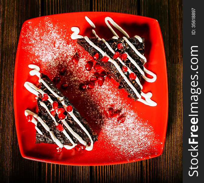 Christmas chocolate cake dessert with pomegranate grains on red plate. Christmas chocolate cake dessert with pomegranate grains on red plate