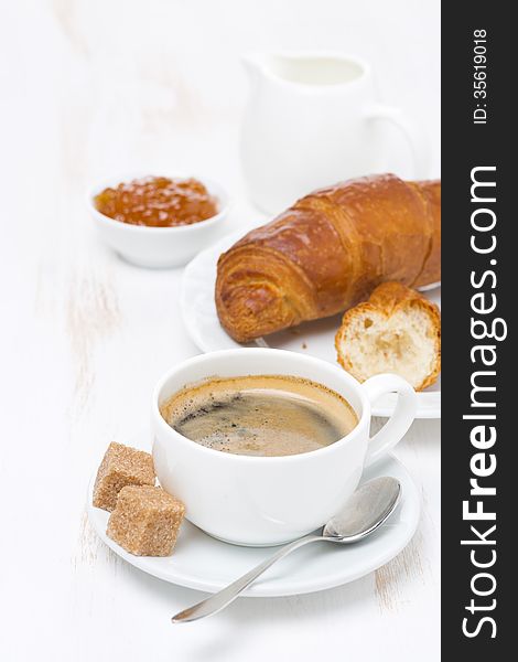 Cup of black coffee and croissants with orange jam, vertical