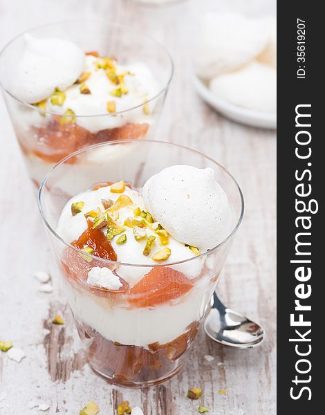 Dessert with canned peaches, whipped cream, meringue and pistachios, vertical