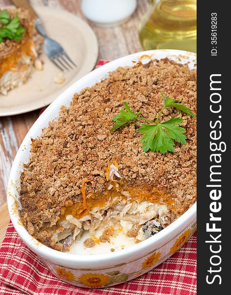 Gratin with fish and pumpkin in a ceramic form, close-up, vertical, top view