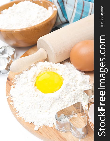 Ingredients for baking cookies - flour, egg and baking forms on wooden board, close-up