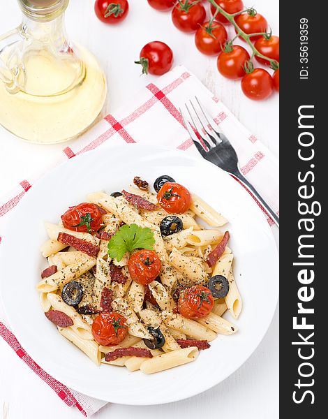 Pasta with sausage, cherry tomatoes and olives, top view, vertical