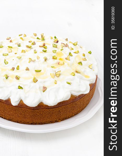 Orange cake with Greek yogurt, honey and pistachios on a plate, close-up